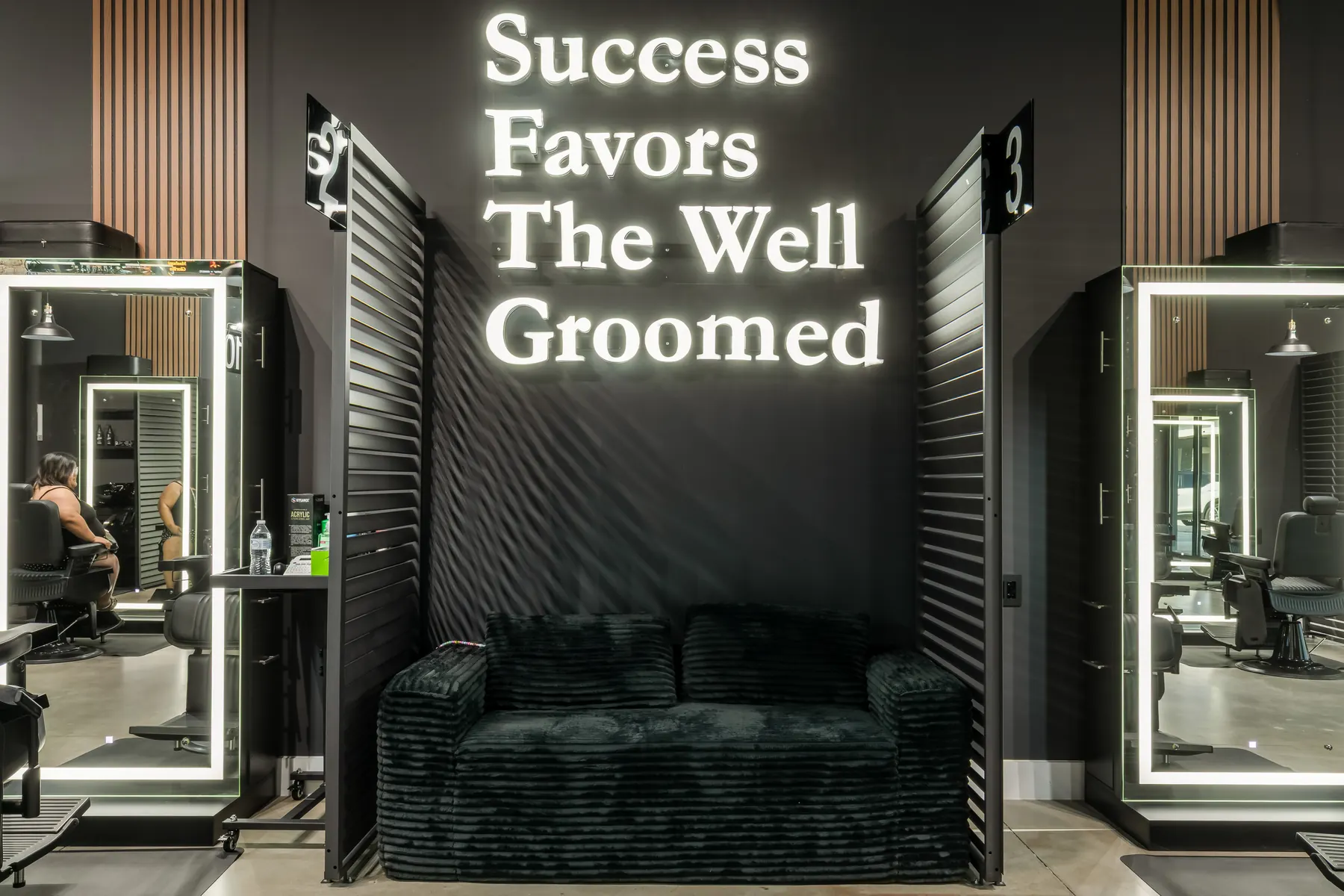 Neon 'Success Favors The Well Groomed' wall above a lounge sofa at DG's Barber Shop